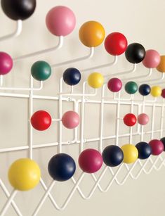 there are many different colored balls hanging on the wall next to each other in this rack