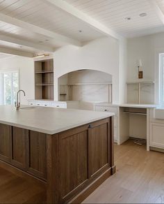 a large kitchen with an island in the middle and wooden cabinets on both sides, along with white walls