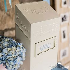 a white box sitting on top of a blue chair next to a vase with flowers