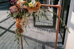 a sign that says welcome to our wedding on the side of a building with flowers