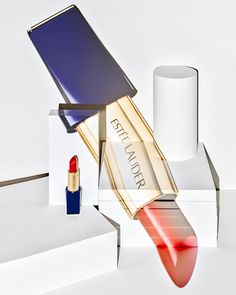 a red lipstick is in front of a white box with a blue lid on it