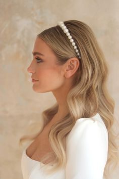 a woman with long blonde hair wearing a white dress and a pearl headband on her head