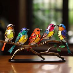 three colorful birds sitting on top of a wooden branch