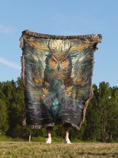 an owl tapestry hanging from the side of a person's legs in front of trees