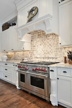 a kitchen with white cabinets and stainless steel stove top oven in the center of the room