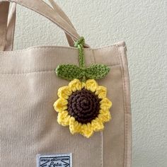 a crocheted sunflower sits on top of a canvas tote bag,