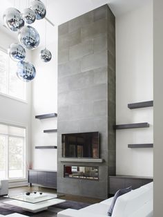 a modern living room with white furniture and large glass balls hanging from the ceiling over the fireplace