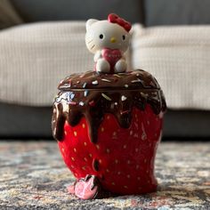 a hello kitty figurine sitting on top of a chocolate covered strawberry with sprinkles