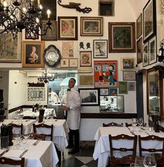 a man standing in the middle of a restaurant with many framed pictures on the wall