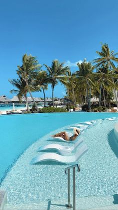 a woman laying on top of a white chaise lounge next to a swimming pool