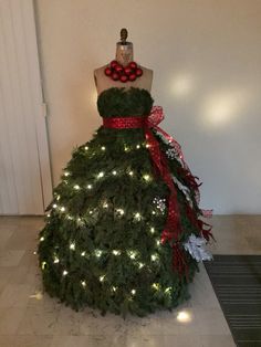 a dress made out of christmas trees with lights on the bottom and red ribbon around it