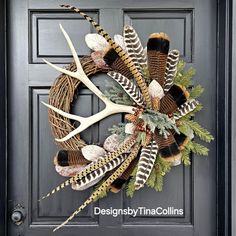 a wreath with antlers, feathers and pine needles is hanging on the front door