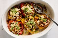 a white bowl filled with stuffed peppers covered in cheese and seasoning next to a spoon