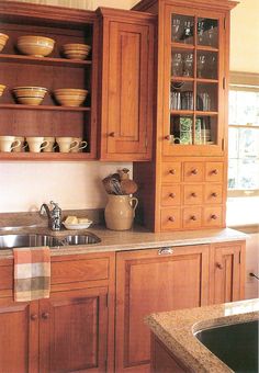 a kitchen with wooden cabinets and dishes on the counter top, along with a sink