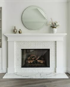 a white fireplace with a mirror above it