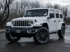 a white jeep is parked on the side of the road in front of some trees