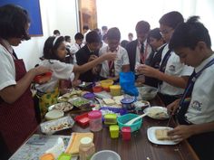 some kids are standing around a table with food on it