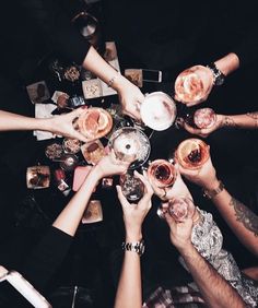 a group of people holding wine glasses in the middle of a table