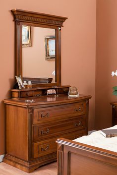 a wooden dresser sitting next to a mirror on top of a wall in a bedroom