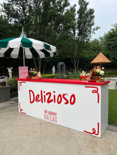 an outdoor delizioso stand with umbrellas and flowers