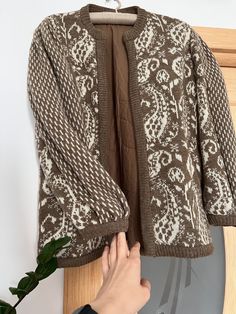 a person holding onto a jacket on a hanger next to a potted plant