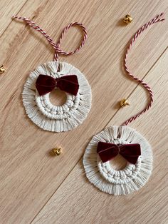 two christmas ornaments with red bows and twine on wooden floor next to each other