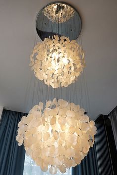 a chandelier hanging from the ceiling in front of a window with blue curtains