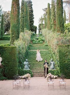 a bride and groom standing in the middle of an outdoor ceremony area with greenery