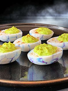 deviled eggs with green and yellow toppings on a plate in the oven, ready to be cooked