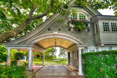 an archway leading to a house with flowers in the window boxes on it's roof