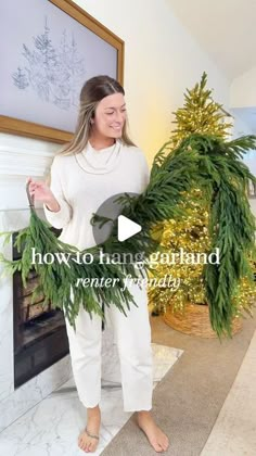 a woman standing in front of a christmas tree with the words how to hang garland on it