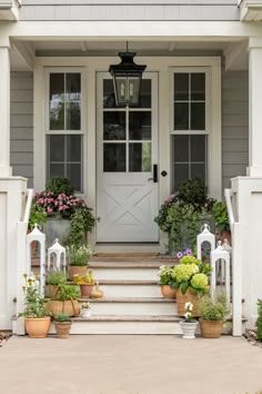 front porch with potted plants and flowers on the steps leading up to the door