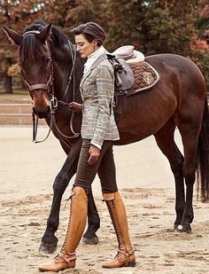 a woman is walking her horse in the dirt