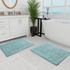 two bathroom rugs on the floor in front of a bathtub and sink with a potted plant