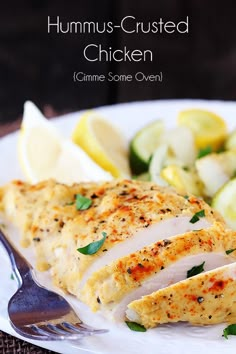 a white plate topped with sliced chicken next to cucumbers and lemon wedges