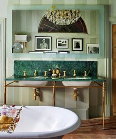 a bathroom with green marble counter tops and gold fixtures on the wall above two sinks