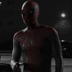 the amazing spider - man is standing in front of his car