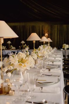 a long table is set with white flowers and place settings