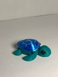 a blue plastic turtle toy sitting on top of a white table next to a black object