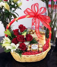 a basket filled with red roses and chocolates