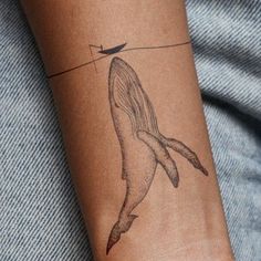 a woman's arm with a whale tattoo on it