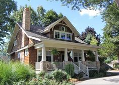 a small house with porches and windows on the front lawn, surrounded by trees