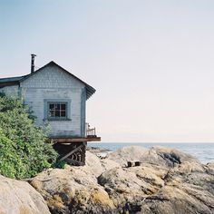 an old house sitting on top of rocks near the ocean