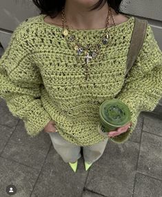 a woman wearing a green knitted sweater and holding a flower