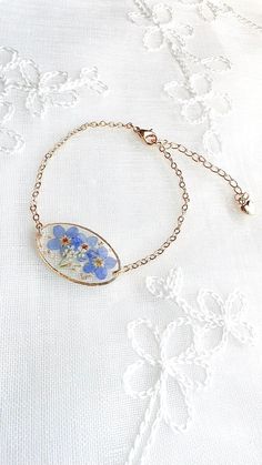 a bracelet with flowers on it sitting on top of a white cloth covered tablecloth