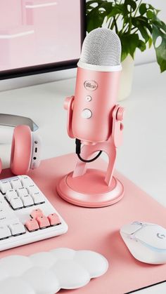 a pink microphone sitting on top of a desk next to a computer keyboard and mouse