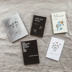 four books laying on top of a bed next to each other with writing on them