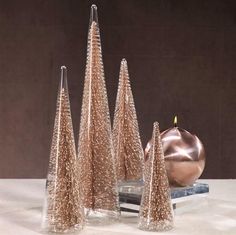 three small christmas trees sitting on top of a table next to a candle and other decorations