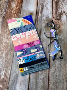 a pair of glasses sitting on top of a wooden table next to a colorful wallet