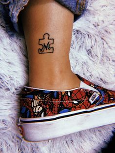 a woman's foot with a tattoo that has a puzzle piece tattooed on it